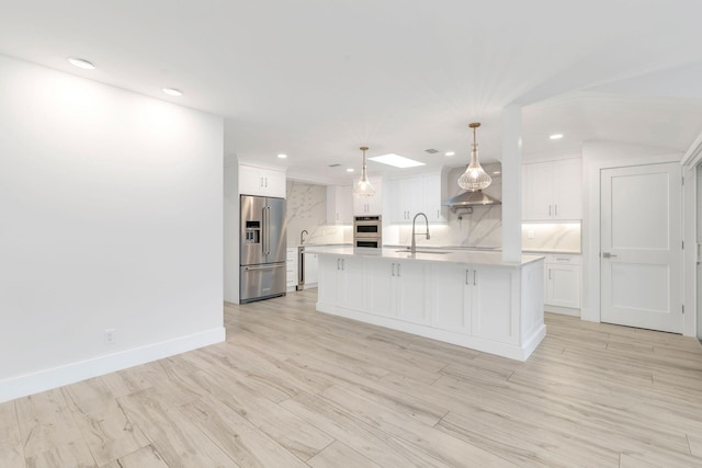 kitchen featuring appliances with stainless steel finishes, tasteful backsplash, a kitchen island with sink, pendant lighting, and white cabinets