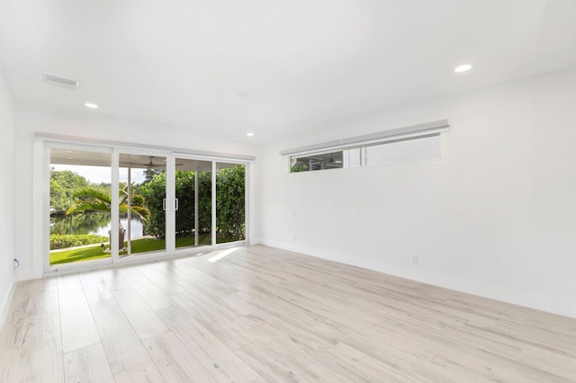 spare room featuring a water view and light hardwood / wood-style flooring