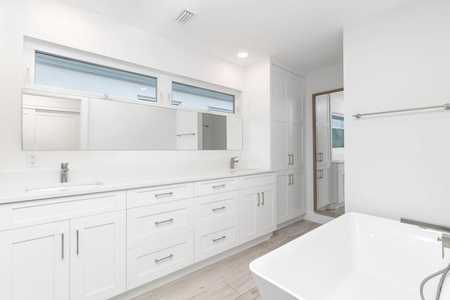 bathroom with hardwood / wood-style floors, vanity, and a bathing tub