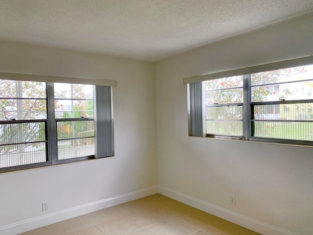 unfurnished room with a healthy amount of sunlight, a textured ceiling, and light tile patterned floors