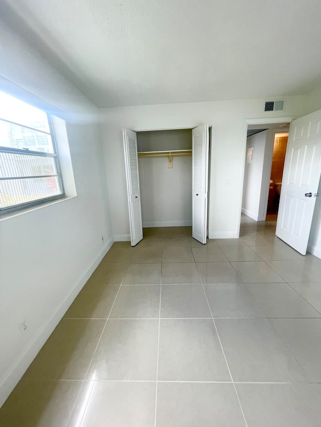 unfurnished bedroom with a closet and light tile patterned floors