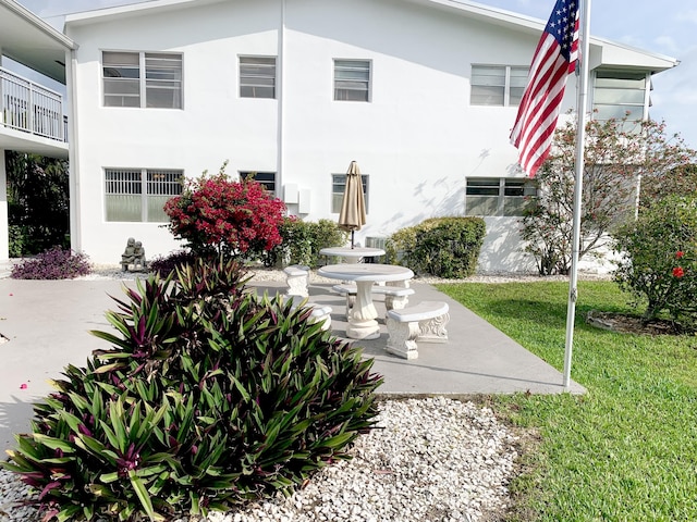 rear view of property with a yard, a patio area, and stucco siding