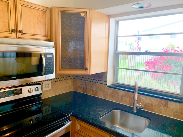 kitchen featuring appliances with stainless steel finishes, tasteful backsplash, sink, and dark stone counters