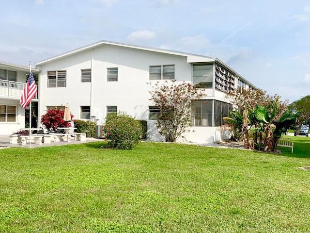 exterior space with a balcony, a yard, and a patio area