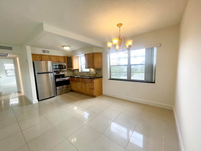 kitchen with pendant lighting, appliances with stainless steel finishes, a textured ceiling, and plenty of natural light