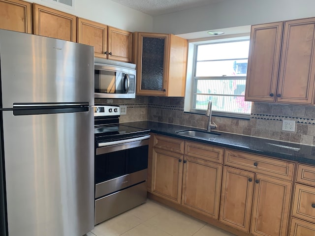 kitchen with backsplash, light tile patterned flooring, appliances with stainless steel finishes, and sink