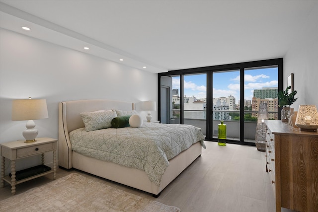 bedroom featuring light hardwood / wood-style floors, access to outside, and floor to ceiling windows