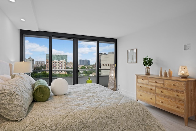 bedroom with hardwood / wood-style floors, a wall of windows, and multiple windows