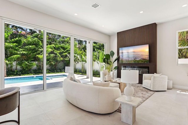 living room with a large fireplace, recessed lighting, light tile patterned floors, and baseboards