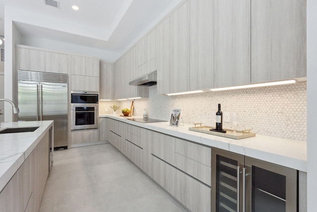 kitchen with modern cabinets, a sink, stainless steel appliances, backsplash, and light stone counters
