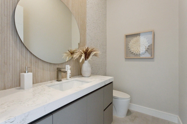 half bathroom featuring vanity, baseboards, and toilet
