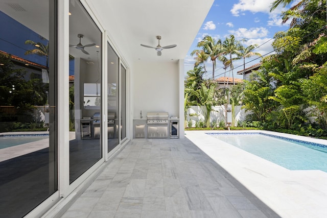 view of swimming pool with a grill, an outdoor kitchen, ceiling fan, fence, and a patio area
