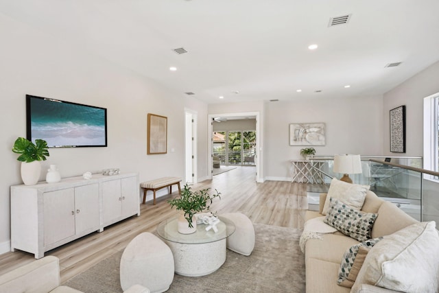 living room featuring light wood-type flooring, baseboards, and recessed lighting