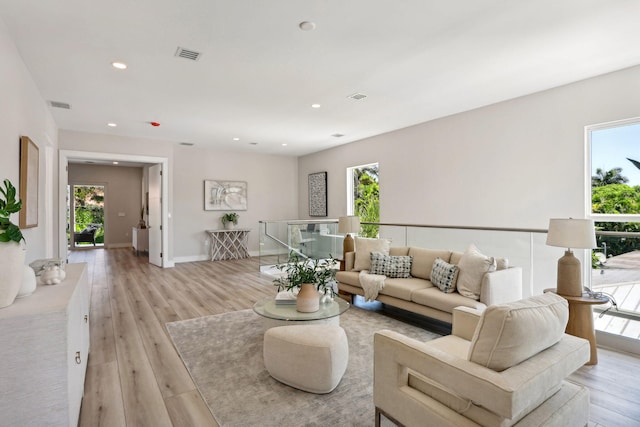living room with plenty of natural light, light wood-style floors, recessed lighting, and baseboards