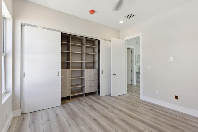 unfurnished bedroom with light wood-style flooring, baseboards, recessed lighting, and a closet