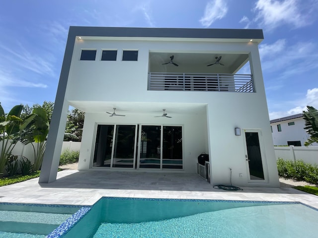 rear view of property with ceiling fan, a fenced in pool, a balcony, and a patio