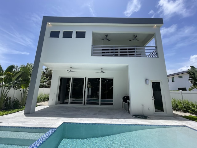 rear view of house with ceiling fan, fence, stucco siding, a patio area, and a pool with connected hot tub
