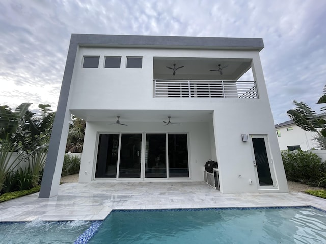 back of property featuring ceiling fan, stucco siding, an outdoor pool, and a patio area