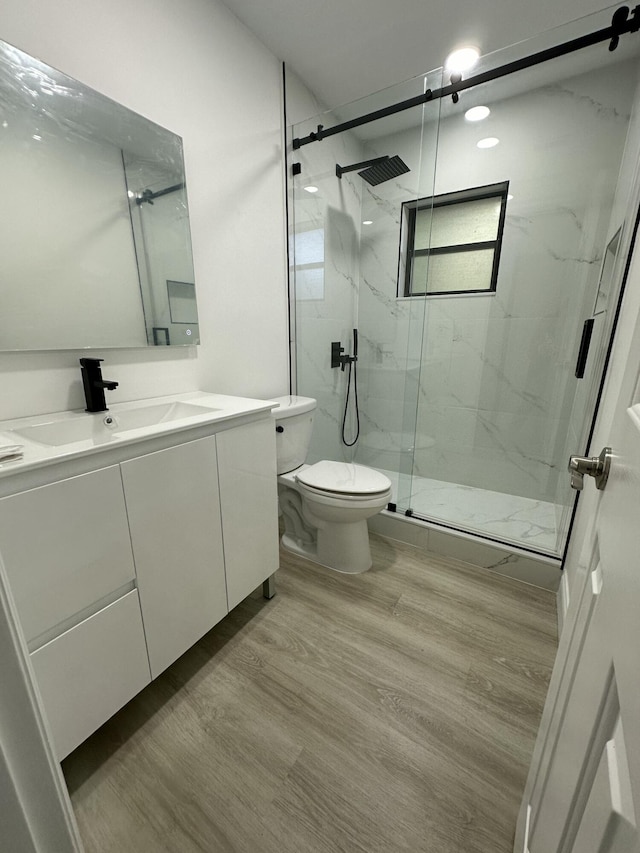 bathroom featuring toilet, a shower with door, vanity, and hardwood / wood-style floors