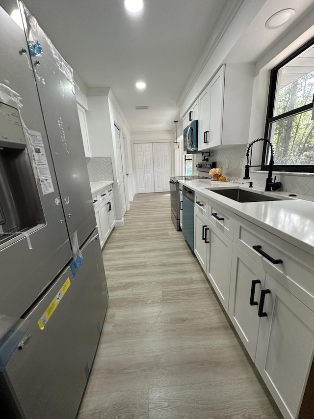 kitchen featuring dishwasher, stainless steel fridge, sink, white cabinetry, and backsplash