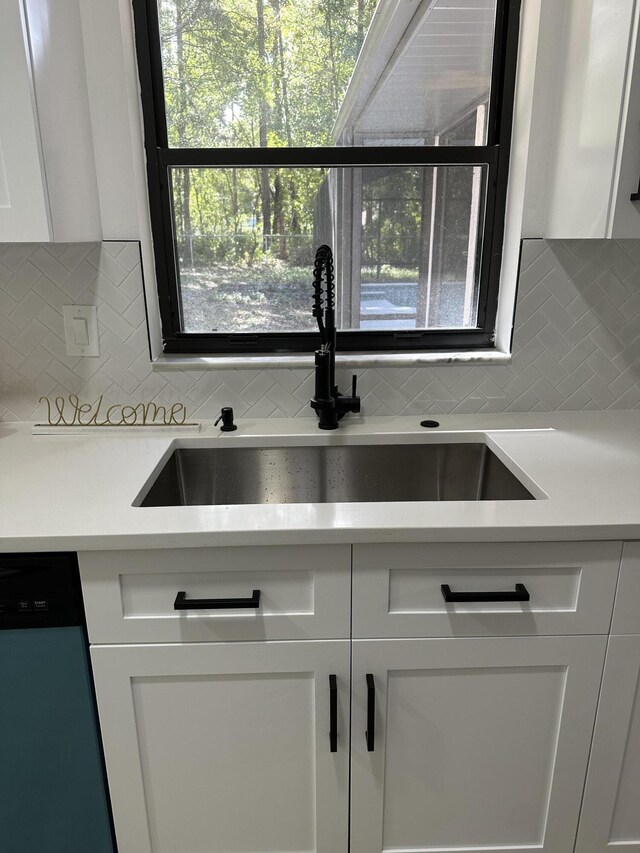 kitchen featuring white cabinets, stainless steel dishwasher, backsplash, and sink