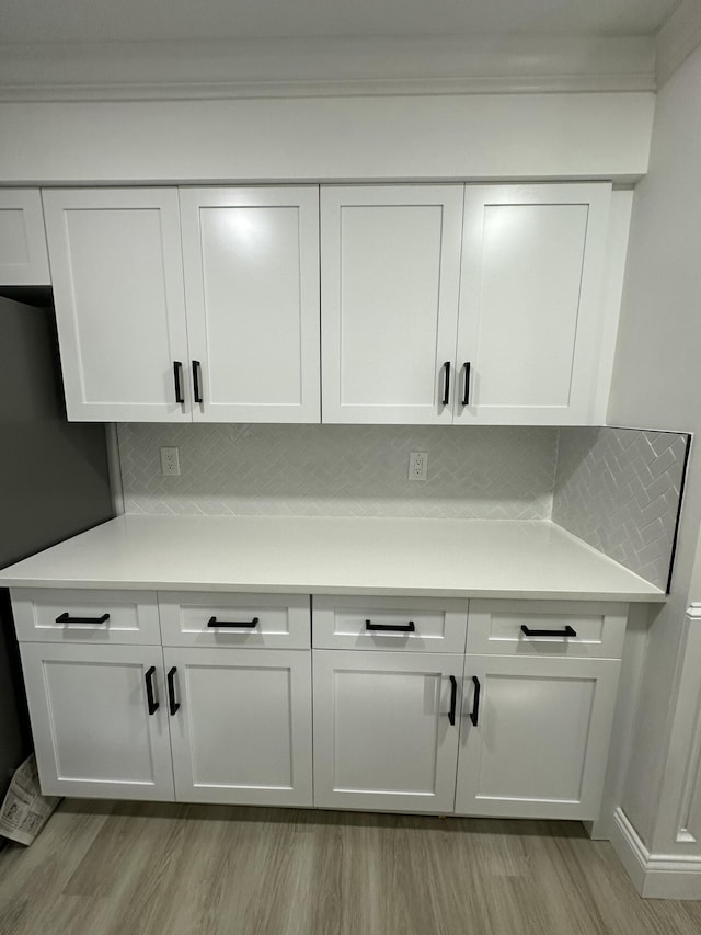 interior details featuring black fridge, decorative backsplash, ornamental molding, and hardwood / wood-style flooring