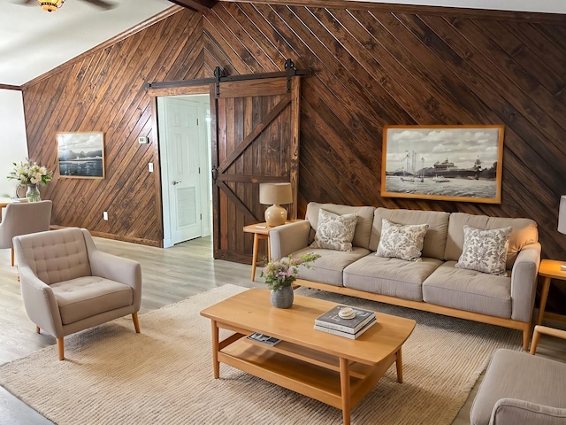 living room with beam ceiling, light wood-type flooring, wooden walls, and a barn door