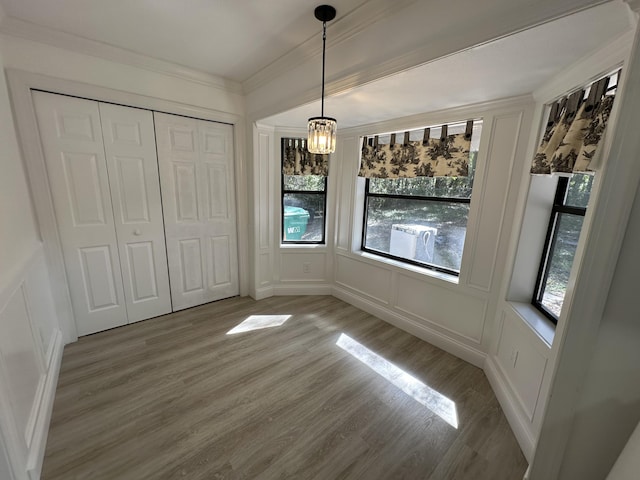 unfurnished dining area with hardwood / wood-style flooring, crown molding, and a chandelier