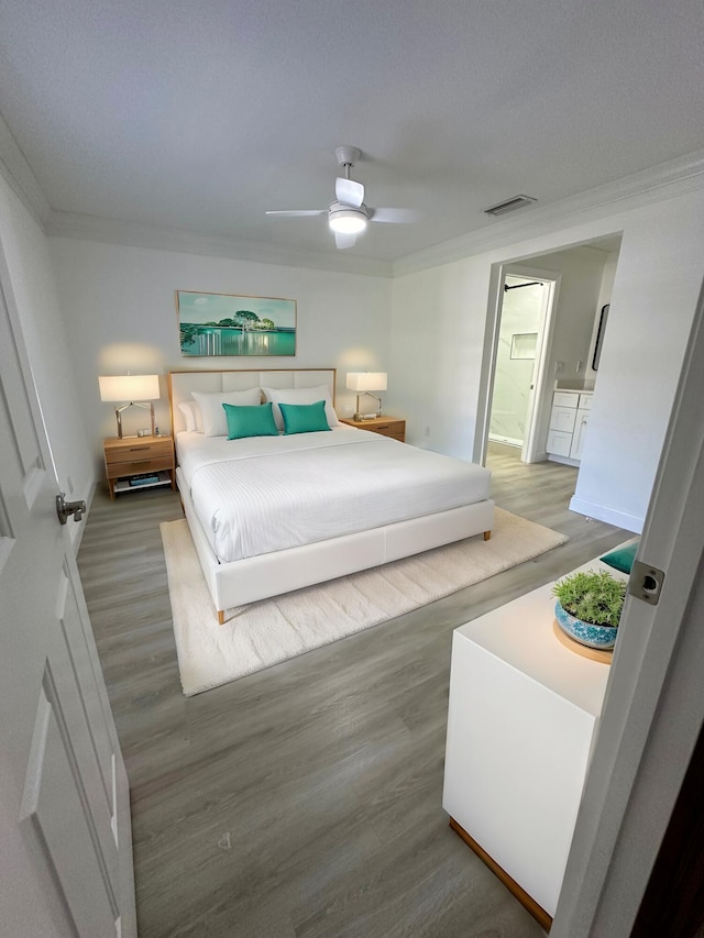 bedroom featuring crown molding, ensuite bath, ceiling fan, and hardwood / wood-style flooring