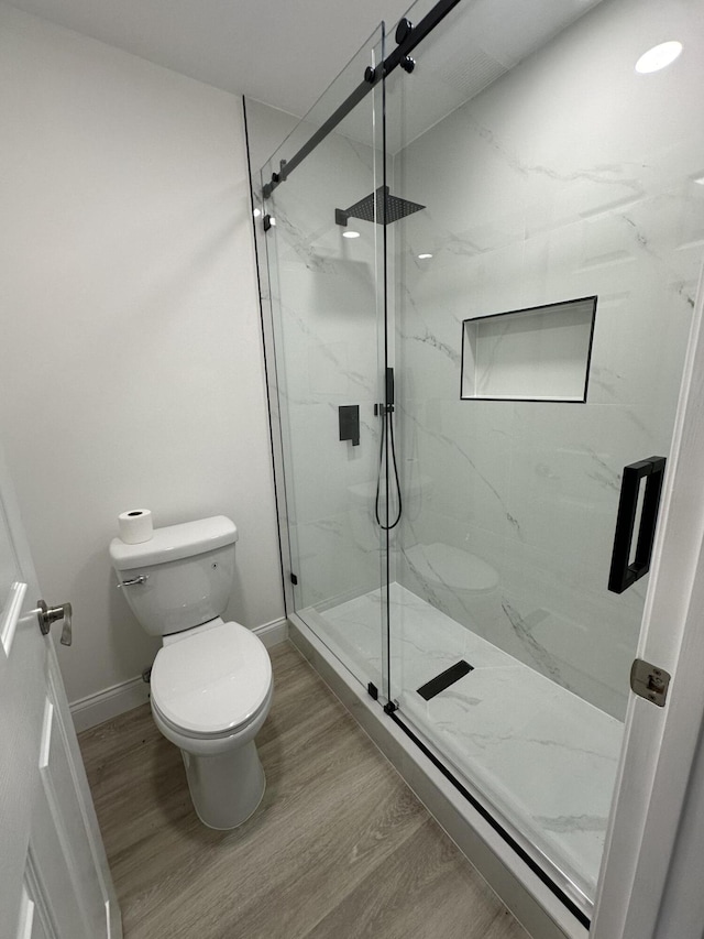 bathroom featuring toilet, an enclosed shower, and wood-type flooring