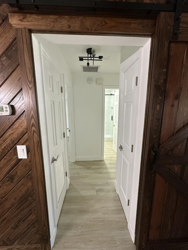 hallway with light wood-type flooring and a barn door