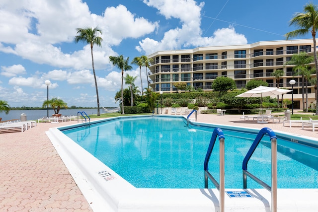 view of pool featuring a water view and a patio