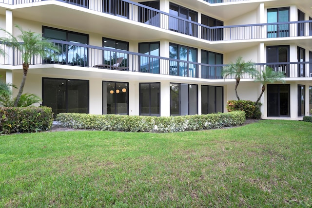 rear view of property featuring a lawn and a balcony