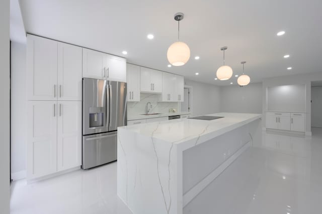 kitchen featuring hanging light fixtures, stainless steel appliances, sink, light stone countertops, and white cabinetry