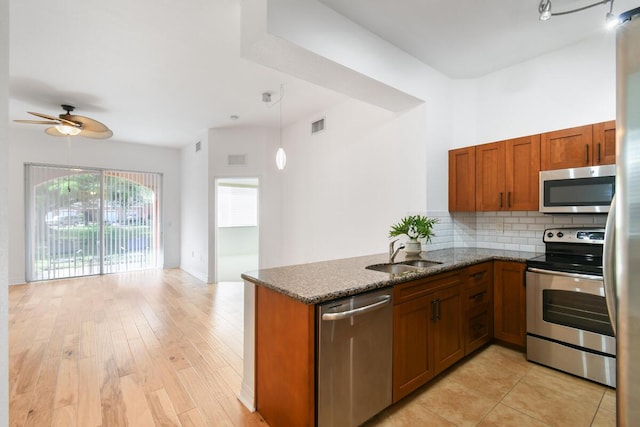 kitchen featuring kitchen peninsula, sink, dark stone countertops, and appliances with stainless steel finishes