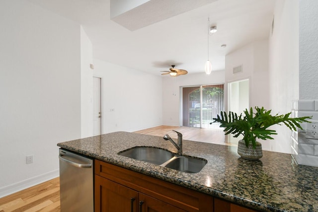 kitchen with ceiling fan, sink, hanging light fixtures, stainless steel dishwasher, and dark stone counters