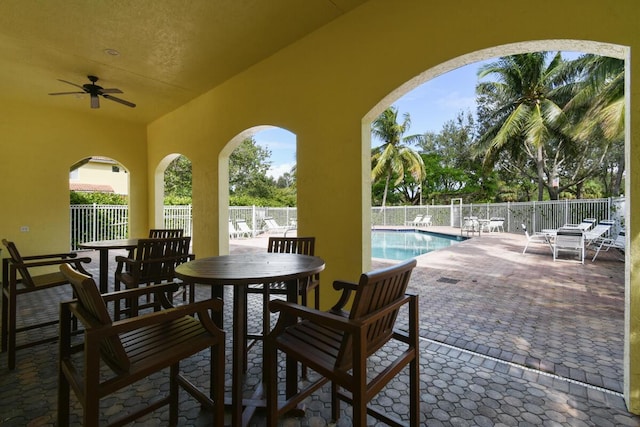 view of patio with ceiling fan and a community pool