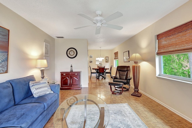 living room with a textured ceiling, light parquet flooring, and ceiling fan with notable chandelier