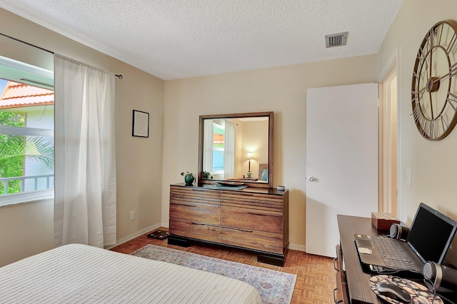 bedroom featuring multiple windows, a textured ceiling, and light parquet flooring