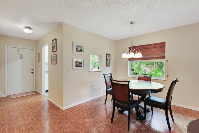 dining area featuring parquet flooring, an inviting chandelier, a textured ceiling, and a healthy amount of sunlight