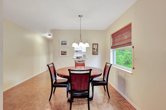 dining area featuring a chandelier, a textured ceiling, and light parquet flooring