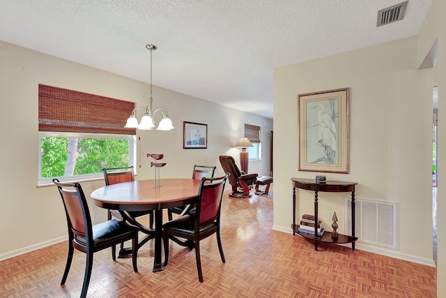 dining room with a notable chandelier, a textured ceiling, and light parquet flooring