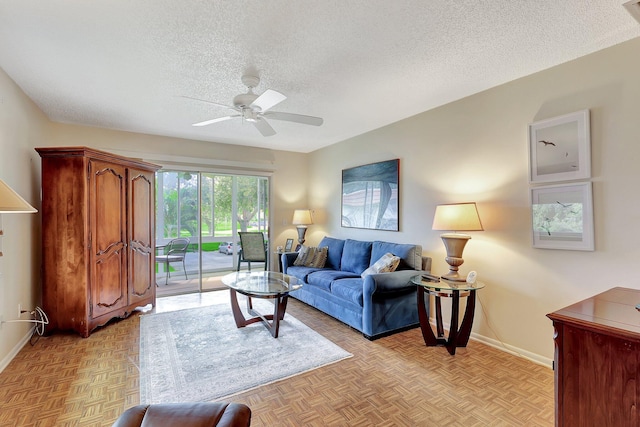 living room with a textured ceiling, light parquet flooring, and ceiling fan