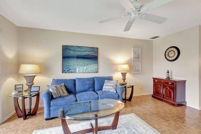 living room featuring a textured ceiling, light parquet flooring, and ceiling fan