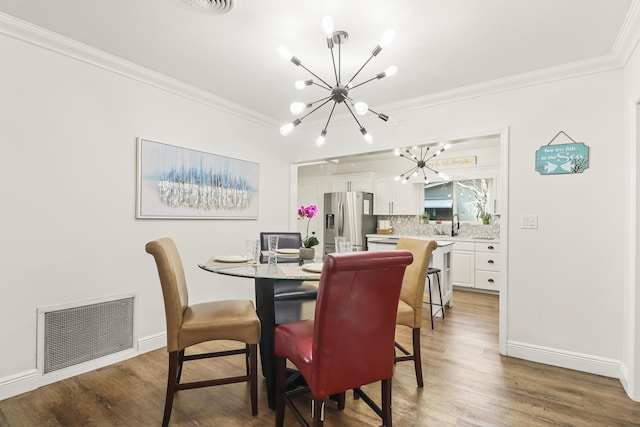 dining area with hardwood / wood-style flooring, crown molding, and a notable chandelier