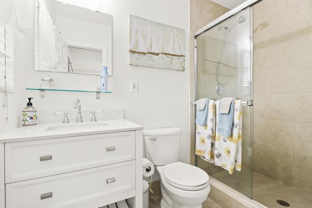 bathroom featuring a shower with door, vanity, and toilet