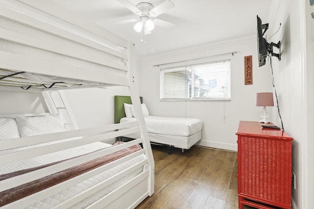 bedroom with ornamental molding, dark wood-type flooring, and ceiling fan