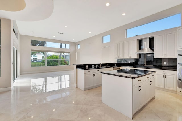 kitchen featuring wall chimney exhaust hood, sink, plenty of natural light, and white cabinets