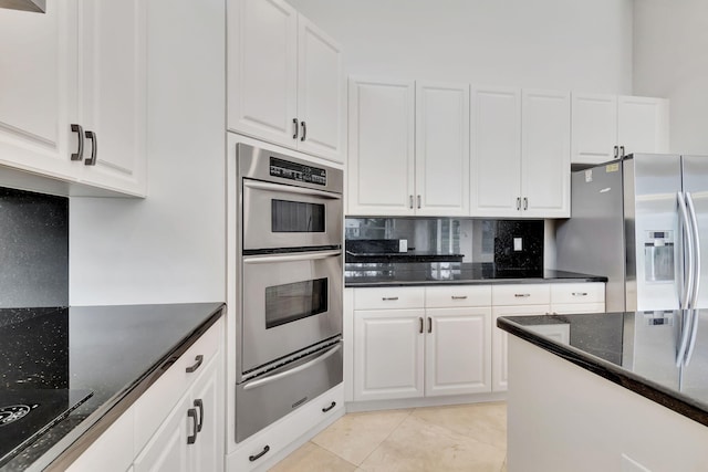 kitchen featuring white cabinets, tasteful backsplash, light tile patterned floors, dark stone counters, and stainless steel appliances