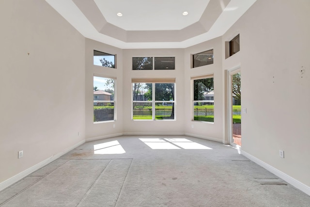 carpeted empty room with a high ceiling and plenty of natural light